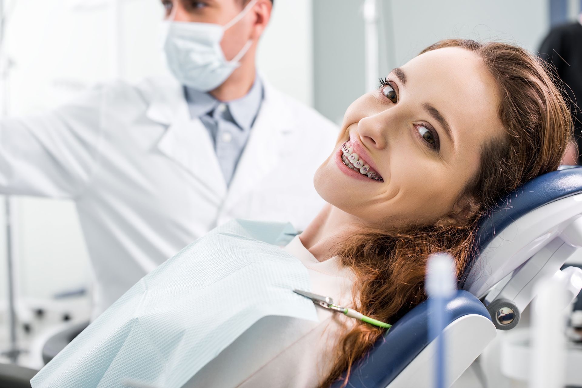 Paziente con apparecchio ortodontico sulla poltrona, accanto all'odontoiatra